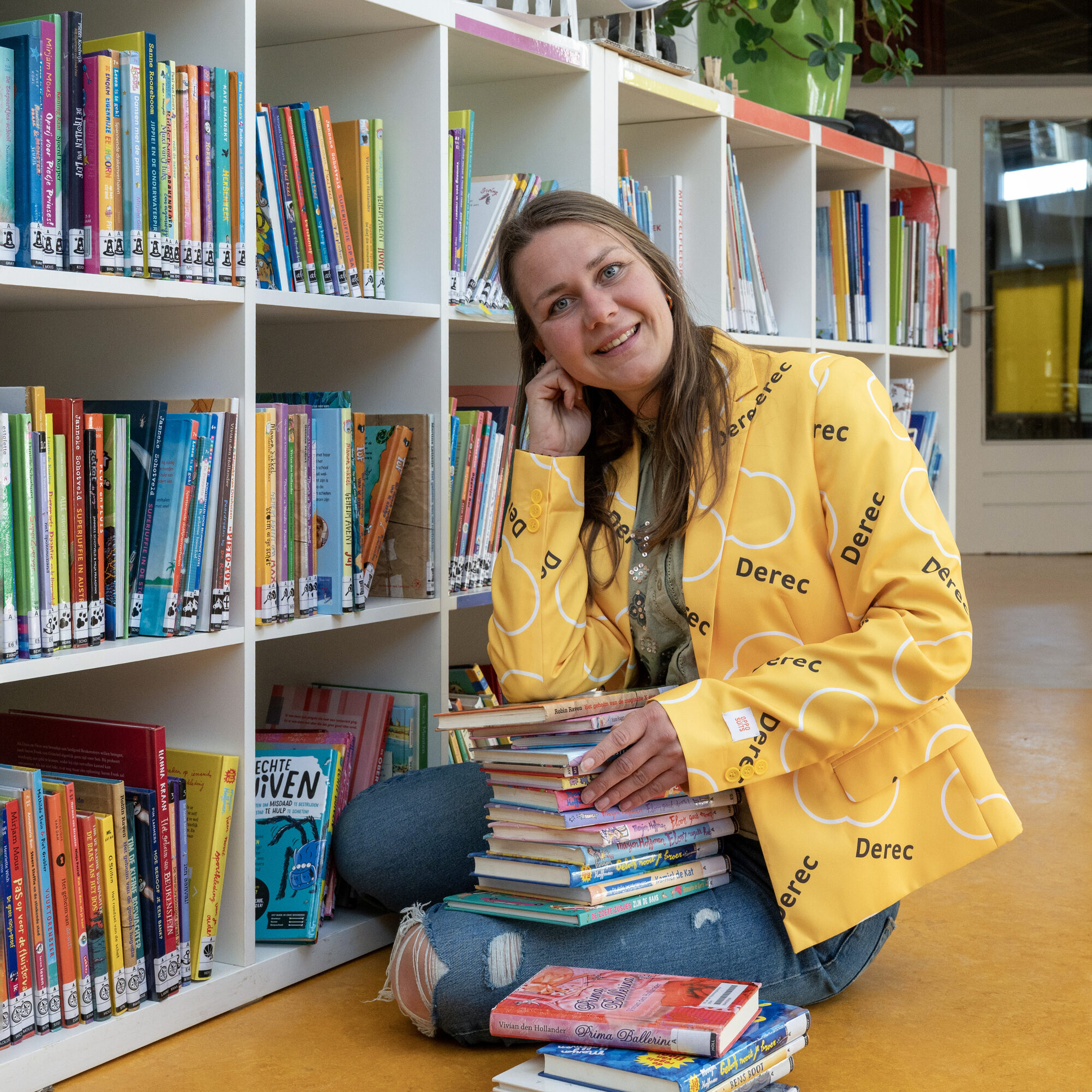 Blije leerkracht met kinderboeken op de basisschool waar ze werkt.